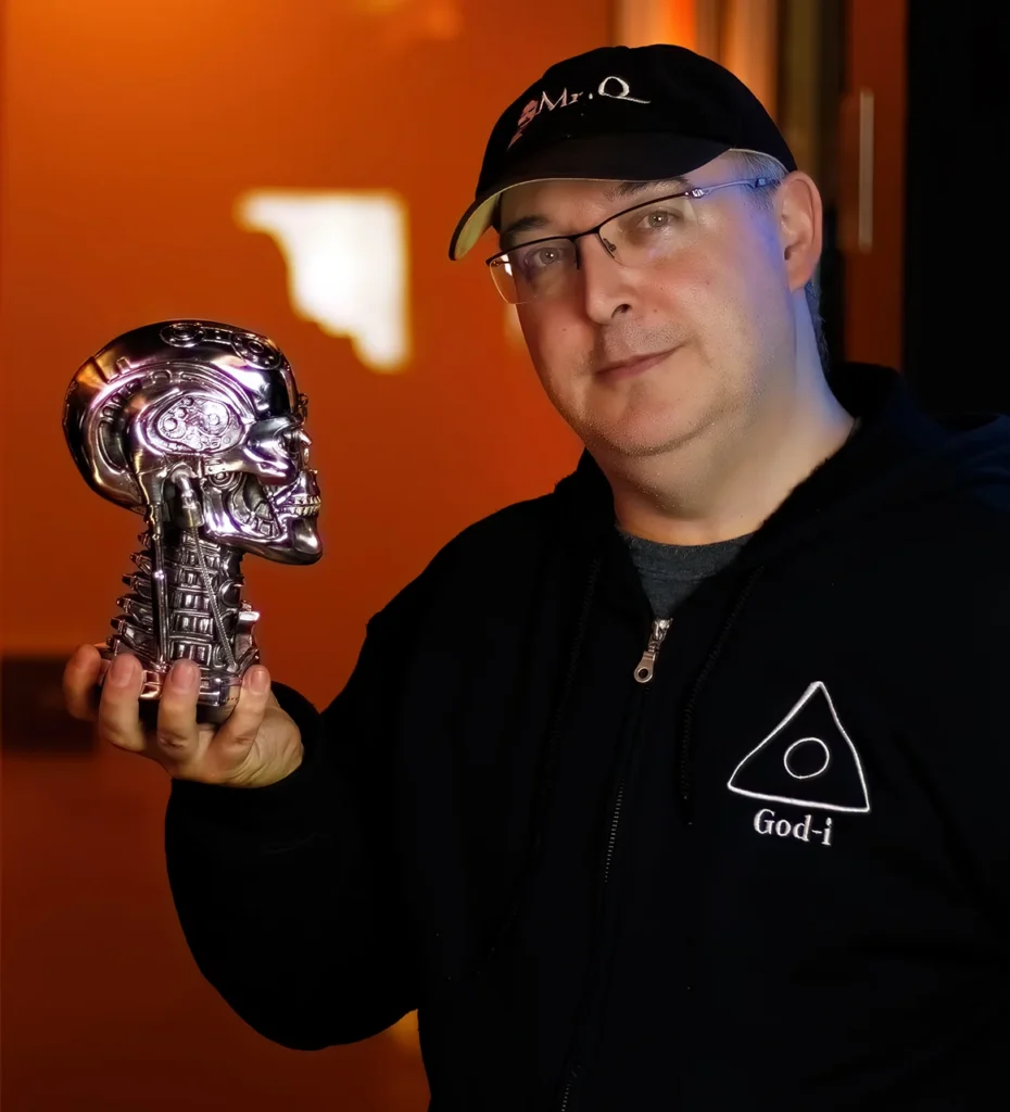 Mr.Q holding a chrome machine-like skull while wearing a God-i hoodie and Mr.Q cap.